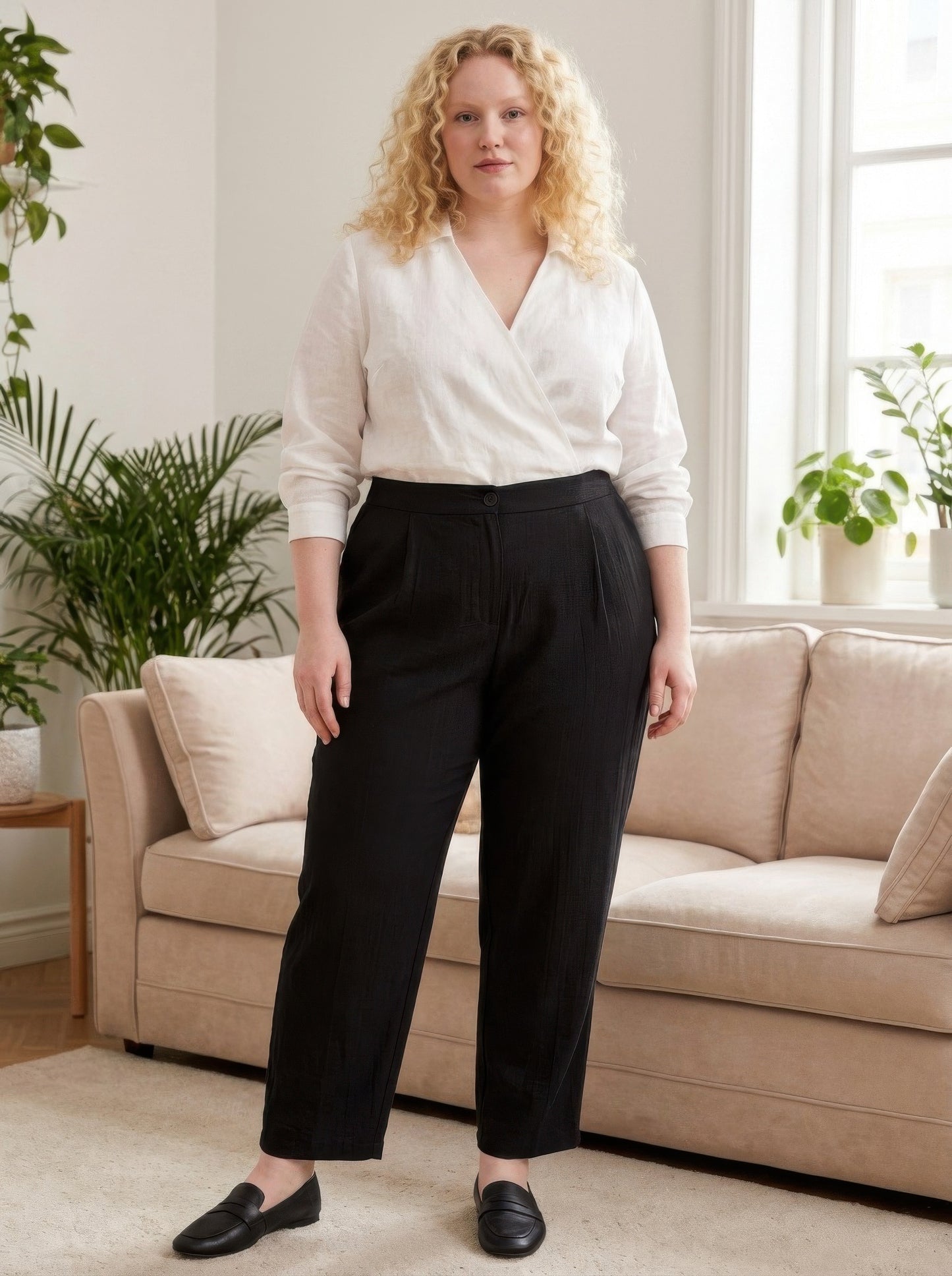Woman wearing a white blouse and black pants in a living room setting