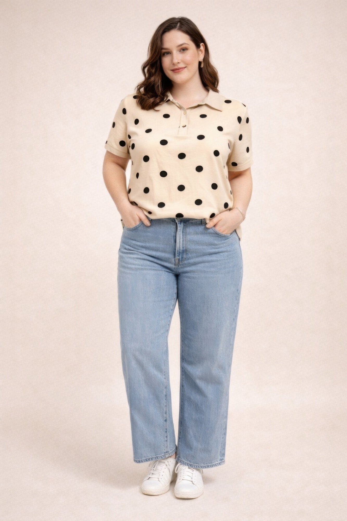 Woman wearing a polka dot shirt and jeans on a beige background